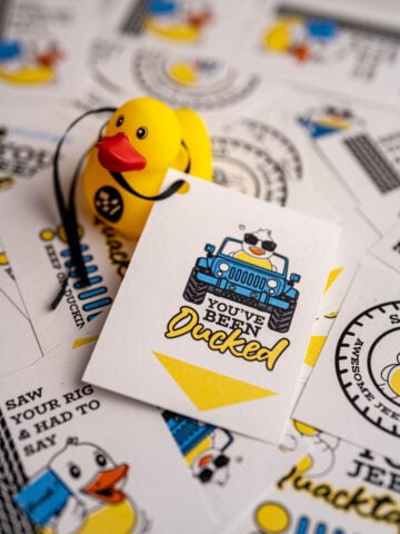 Several printed and cut duck duck jeep tags, and one is tied to a rubber duck.