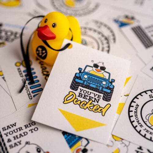 Several printed and cut duck duck jeep tags, and one is tied to a rubber duck.