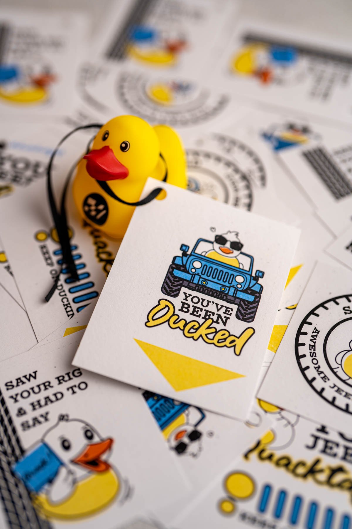 Several printed and cut duck duck jeep tags, and one is tied to a rubber duck.